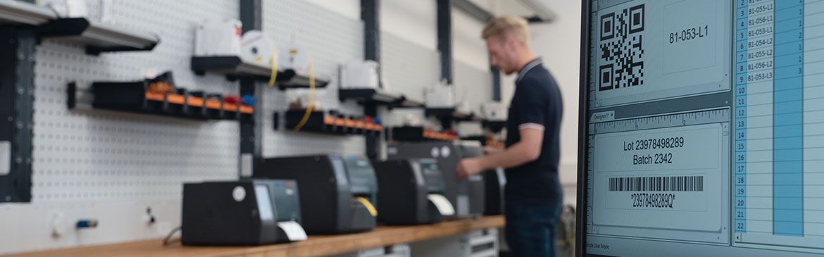 Bilde av en ansatt som jobber med ulike typer termoskrivere fra HellermannTyton med TagPrint Pro programvare