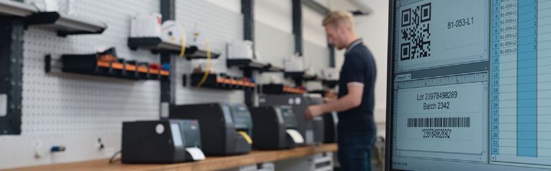 Bilde av en ansatt som jobber med ulike typer termoskrivere fra HellermannTyton med TagPrint Pro programvare